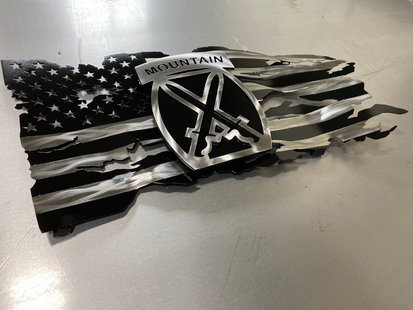 Battle-worn American flag wall art with floating 10th Mountain Division emblem in layered steel.