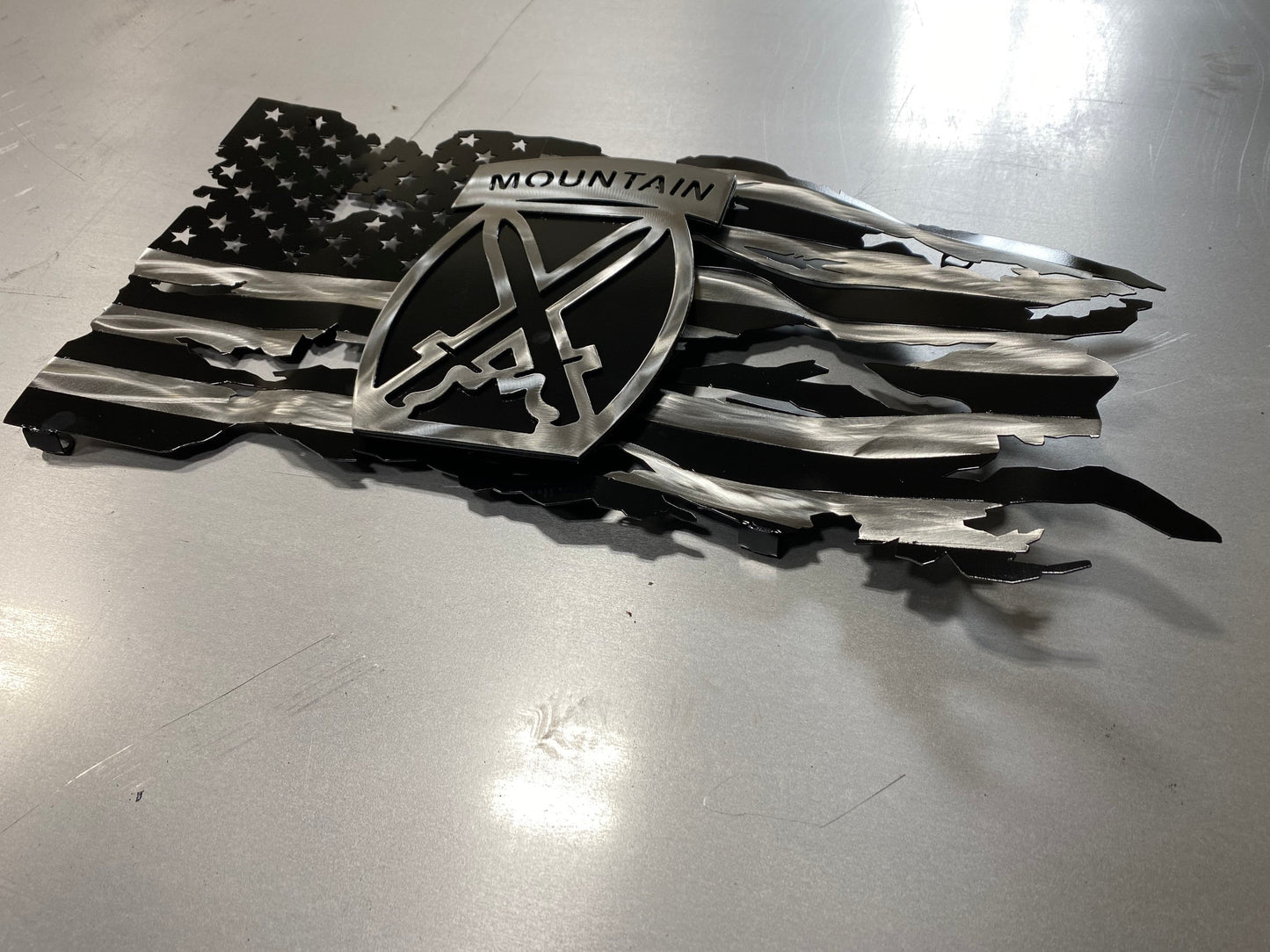 Battle-worn American flag wall art with floating 10th Mountain Division emblem in layered steel.
