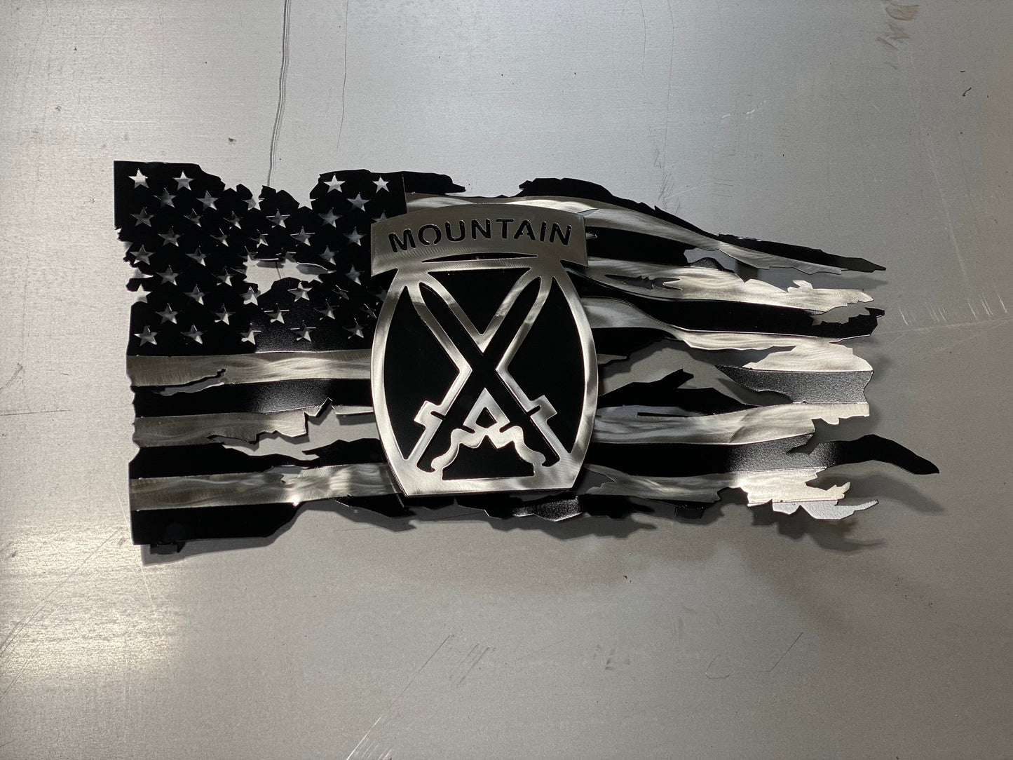 Battle-worn American flag wall art with floating 10th Mountain Division emblem in layered steel.