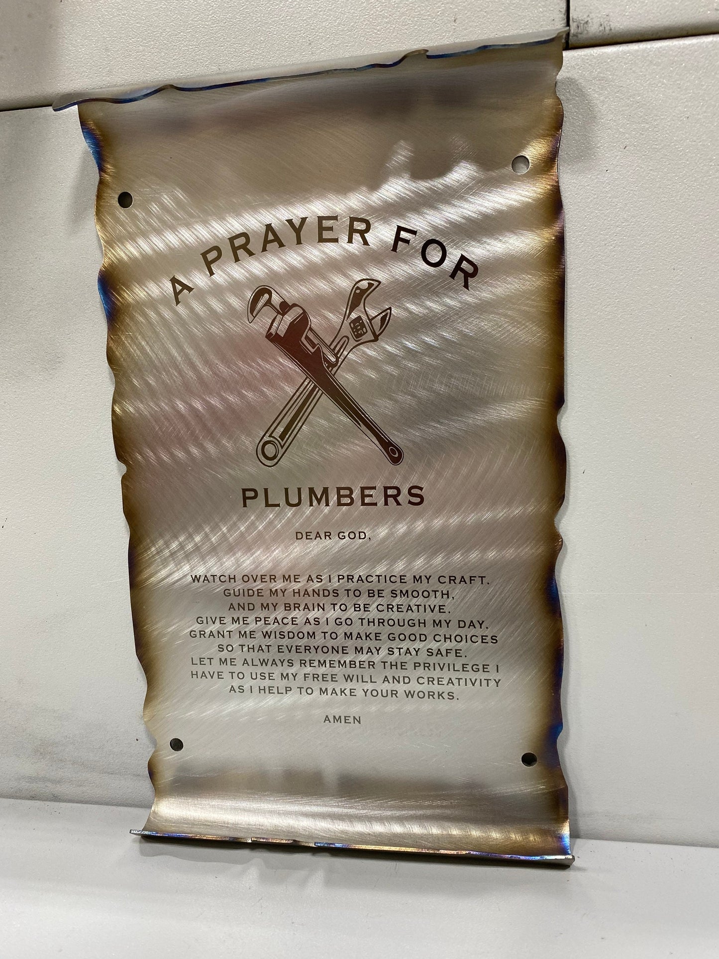 CNC cut metal Plumber’s Prayer scroll with heat patina finish and powder coat, made from American steel