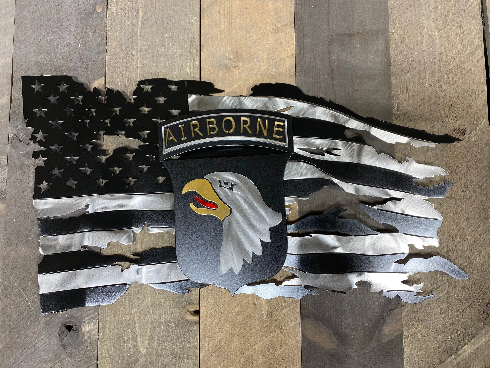 Tattered metal American flag featuring the 101st Airborne Division emblem in black and silver.