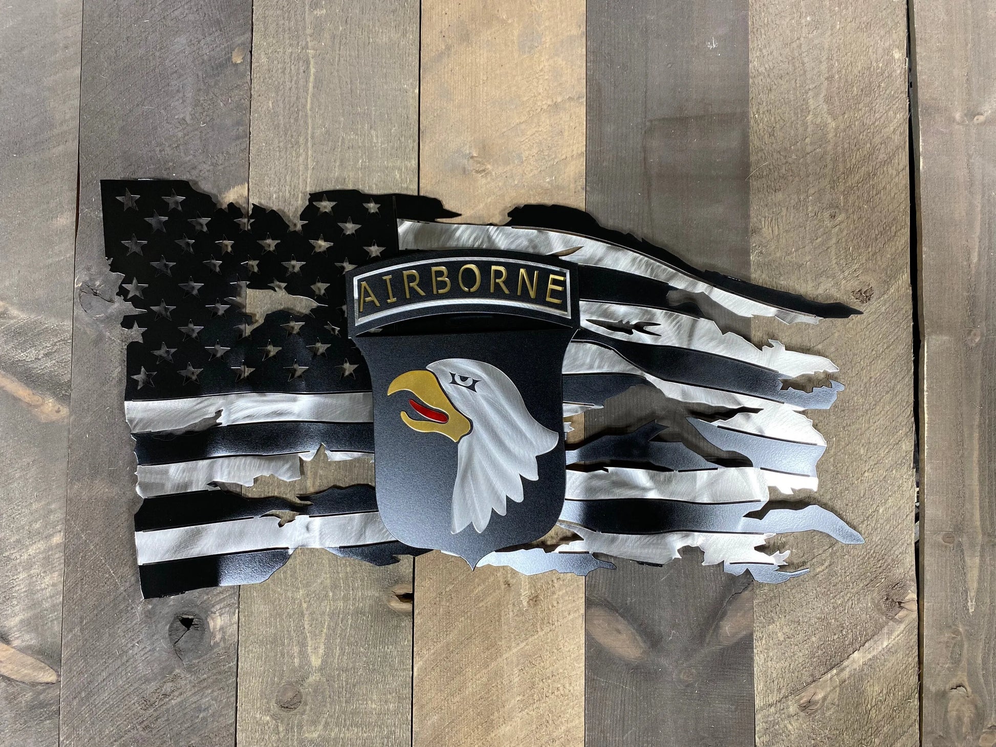 Tattered metal American flag featuring the 101st Airborne Division emblem in black and silver.