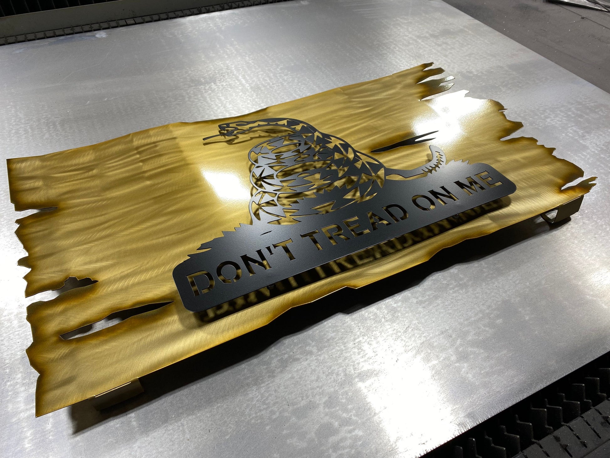 Distressed yellow metal Gadsden flag with Don’t Tread on Me design

