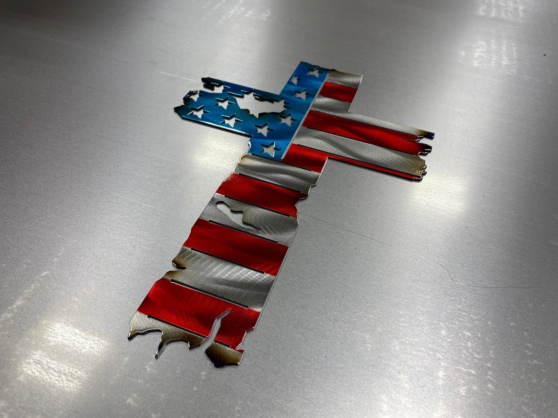 Metal cross wall decor with tattered American flag overlay

