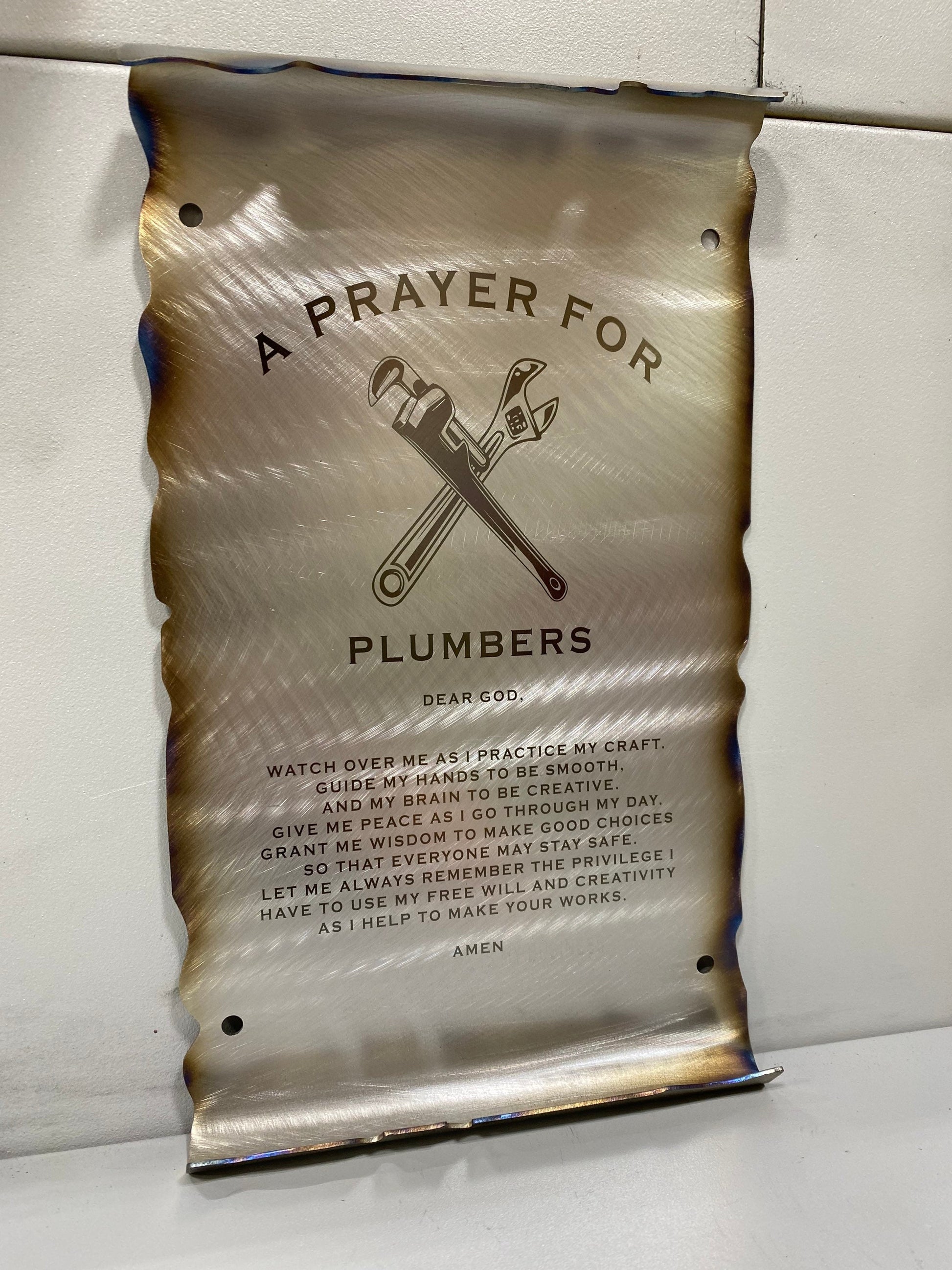 CNC cut metal Plumber’s Prayer scroll with heat patina finish and powder coat, made from American steel