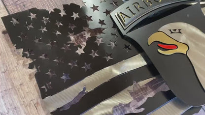 Tattered metal American flag featuring the 101st Airborne Division emblem in black and silver.