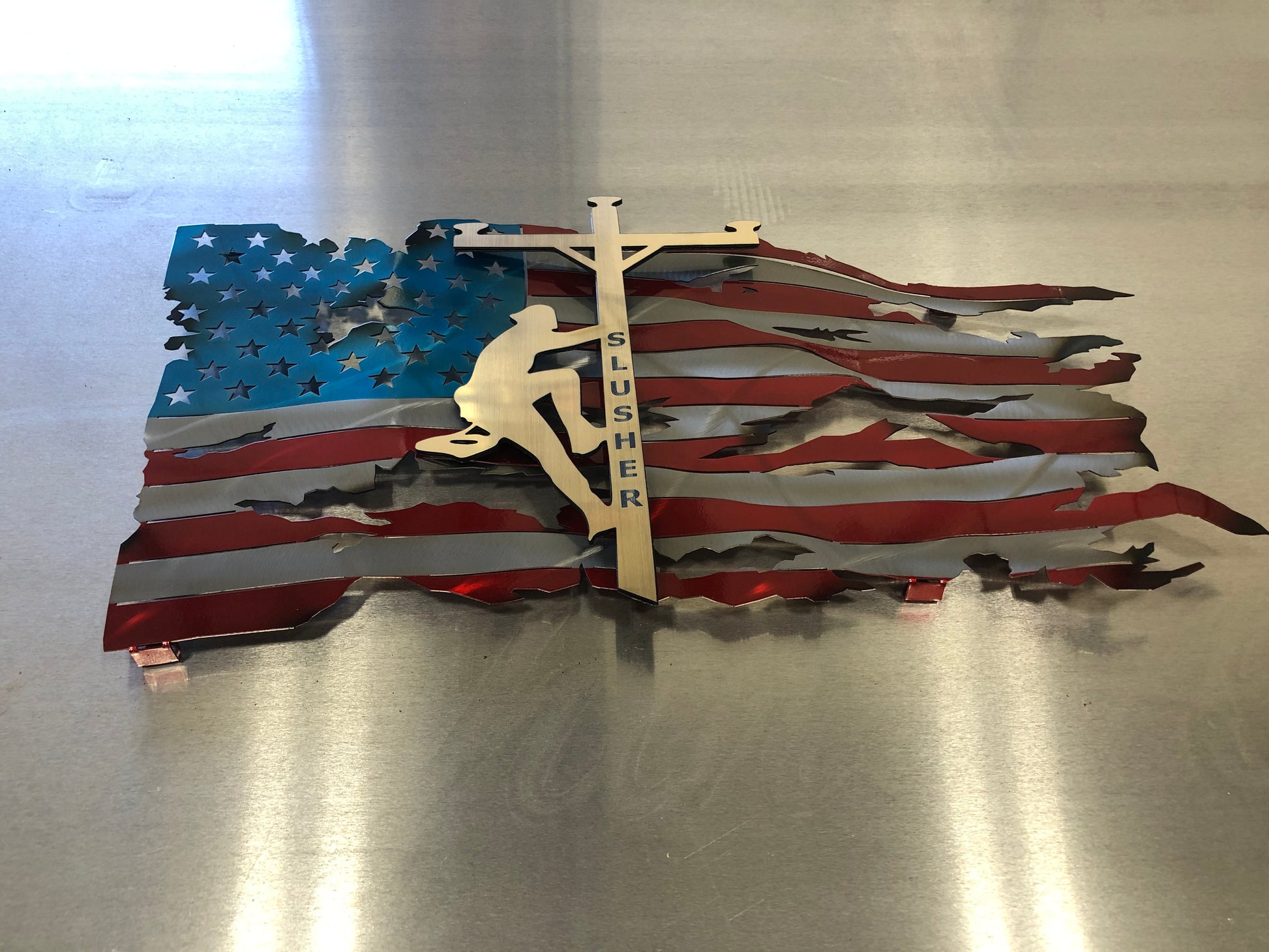 Lineman American Flag featuring a wavy battle-worn metal design with a customizable floating gold lineman. Engraved details available.