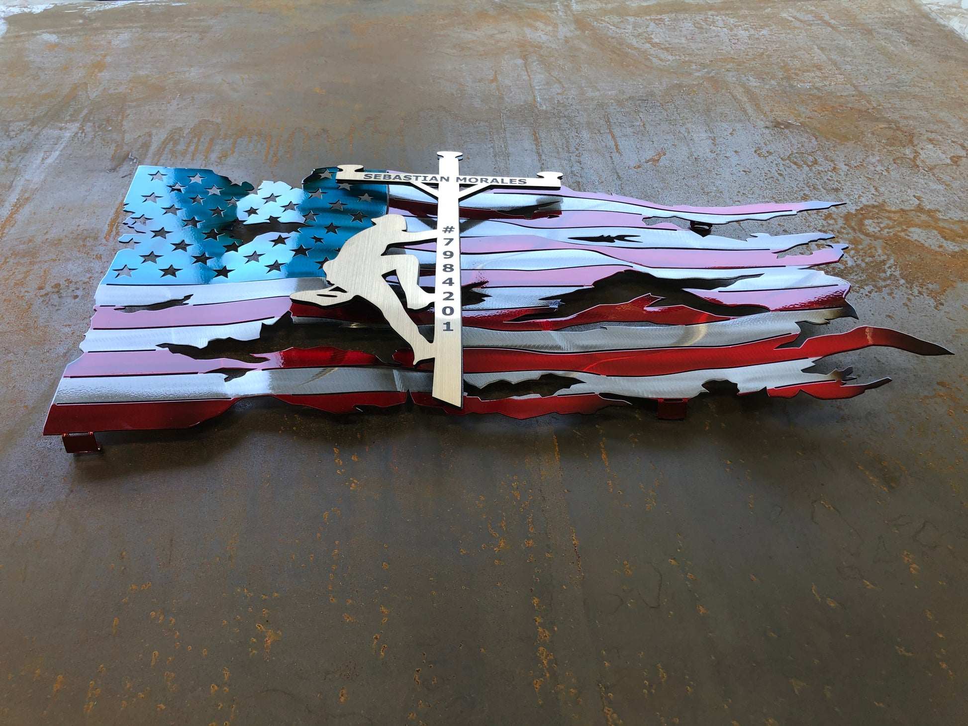 Lineman American Flag featuring a wavy battle-worn metal design with a customizable floating gold lineman. Engraved details available.