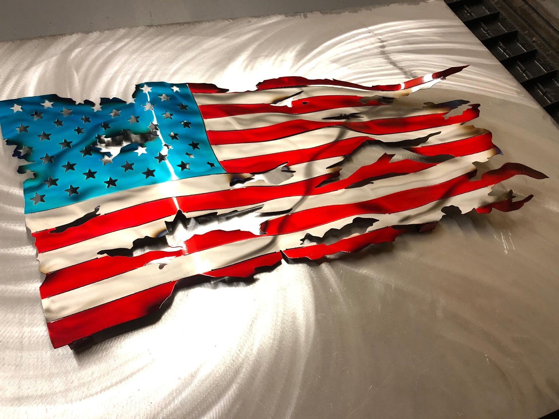 Handcrafted Wavy Battle Worn American Flag made from high-quality American steel with Candy Red and Blue powder coat, 24 inches wide.